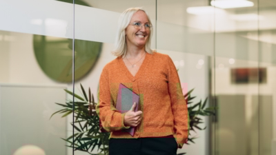 En kvinna står på ett kontor och håller en surfplatta.